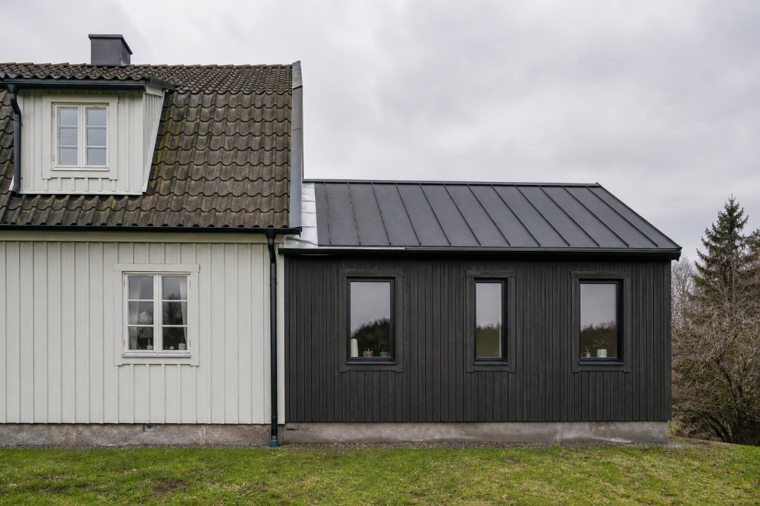 Exempelbild: Tillbyggnad utifrån i gråväder, hela fasaden i bild, nytt och gammalt möts i mitten.